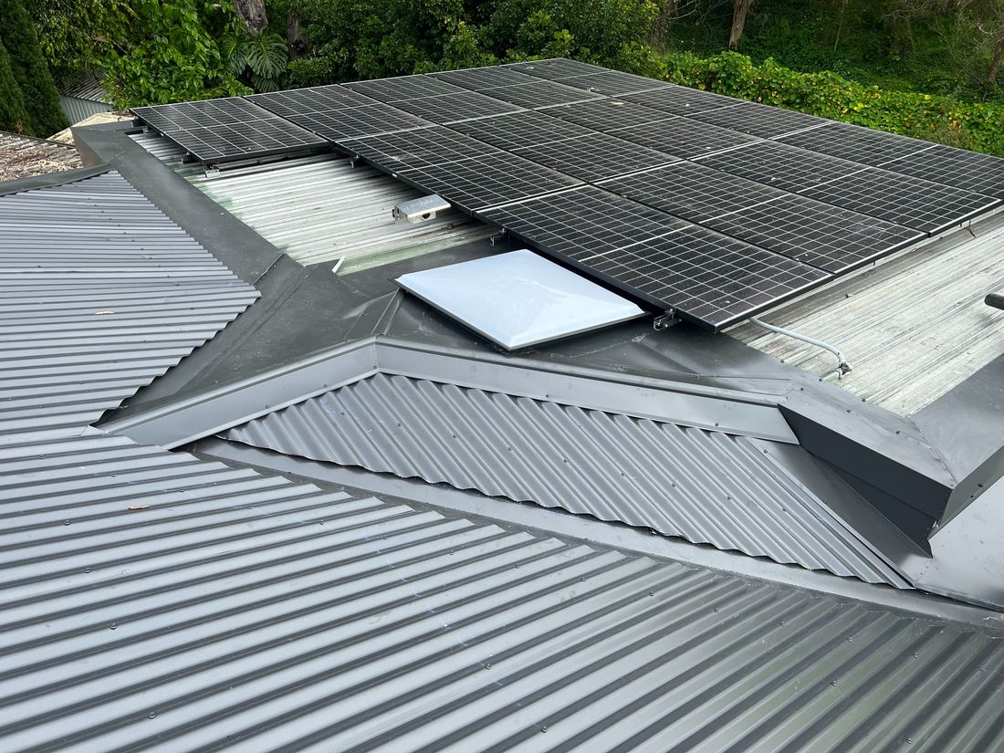 Metal roof edge and flashing work around a skylight and solar panels