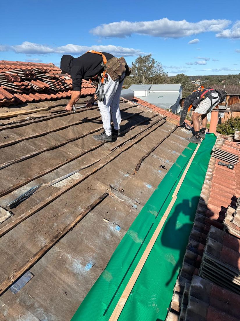 Roofers relaying tiles during a roof restoration