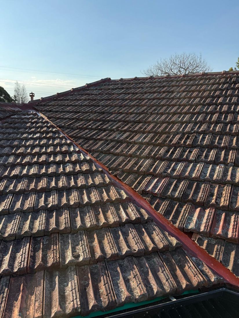 Repaired roof valley flashing between aged terracotta roof tiles